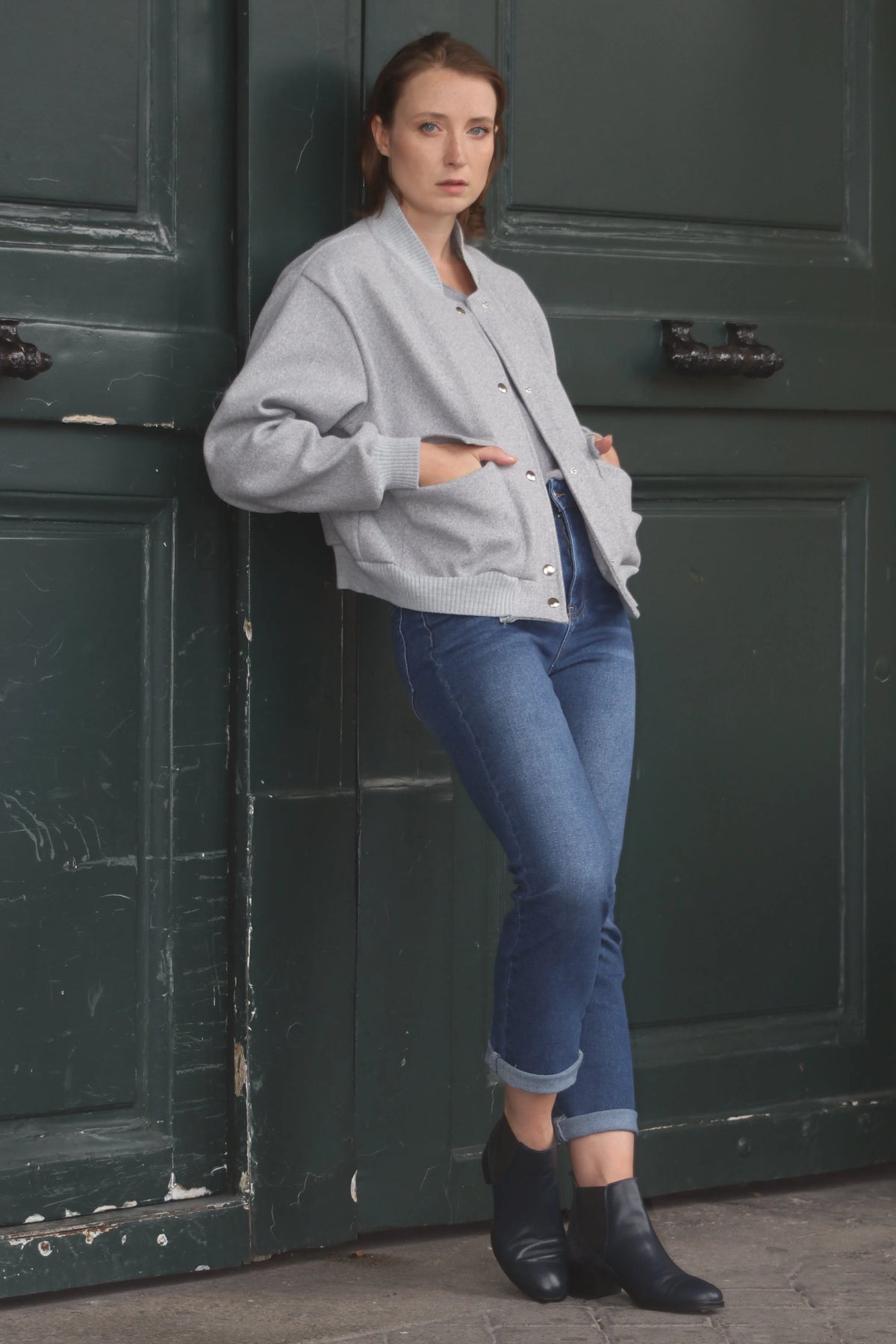 Femme portant un blouson gris oversize, un jean bleu et des bottines noires.