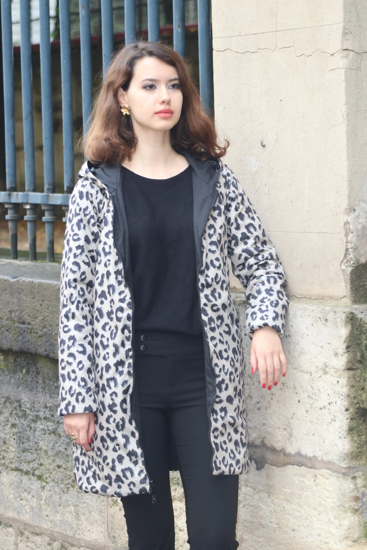 Femme portant un manteau imprimé léopard, un haut noir et un pantalon noir.