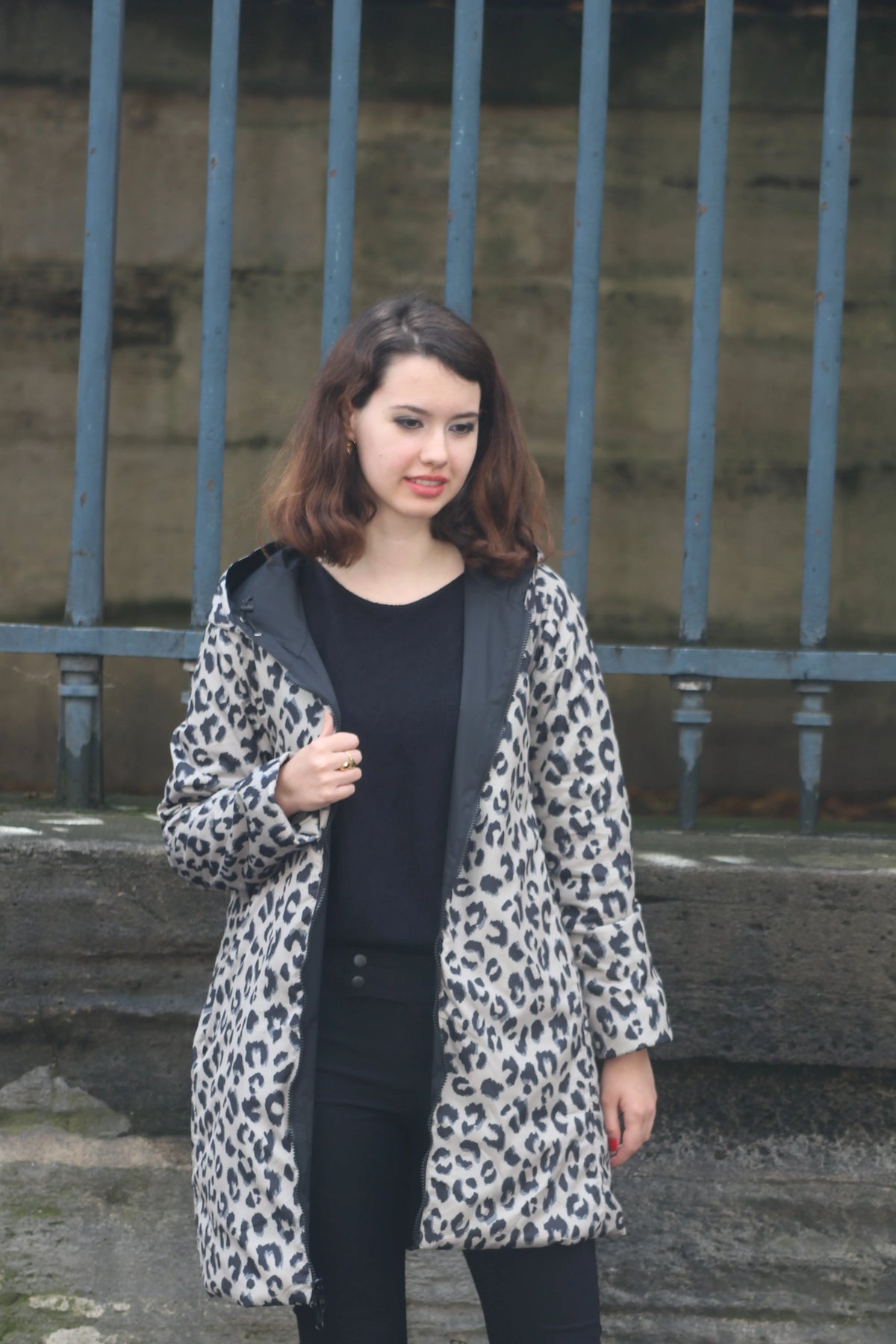 Femme portant un manteau imprimé léopard gris et noir sur un haut noir.