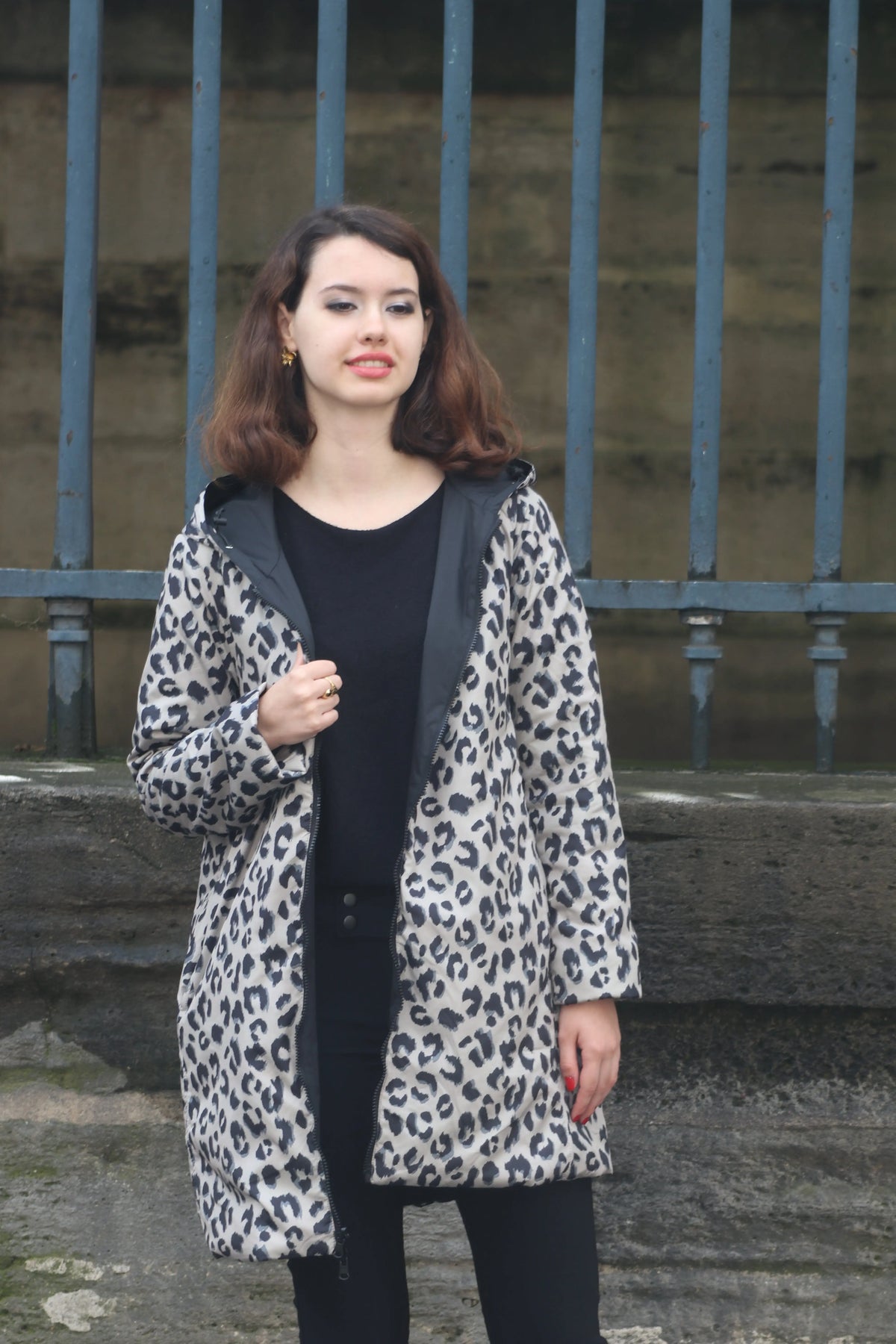 Femme portant un manteau à imprimé léopard gris et noir sur un haut noir.