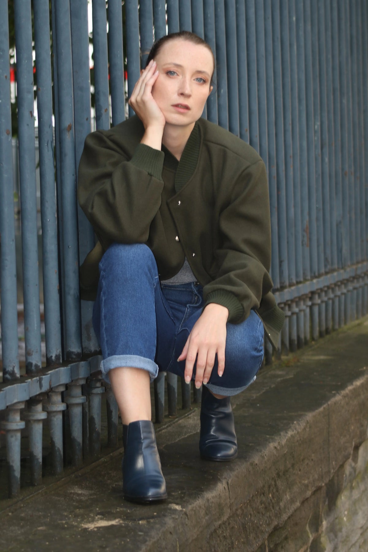 Femme portant une veste bomber vert olive, jean bleu et bottines noires.
