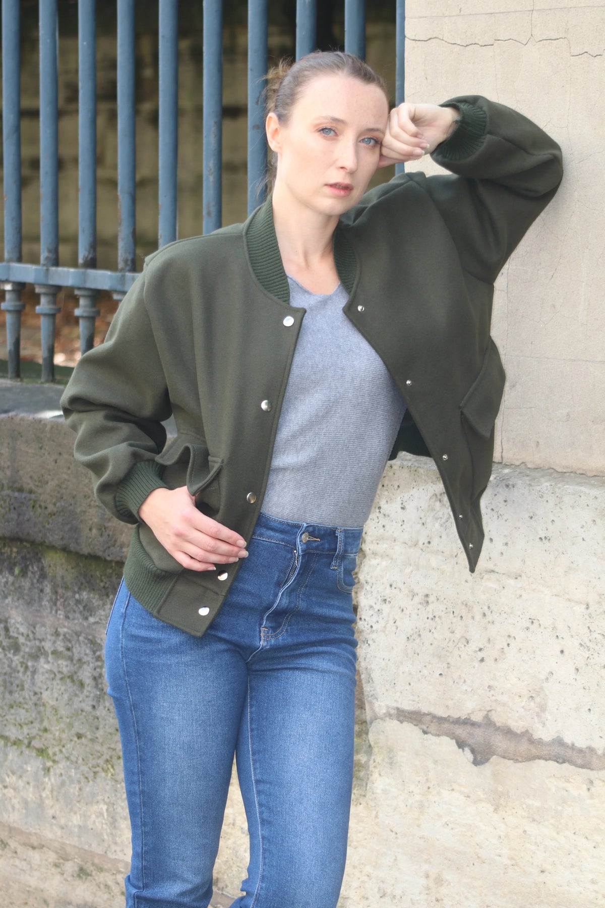 Femme portant un bomber vert olive, t-shirt gris et jean bleu ajusté.