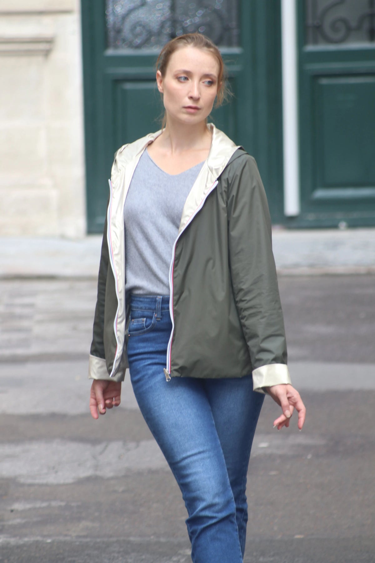 Femme portant une veste légère kaki, un t-shirt gris et un jean bleu