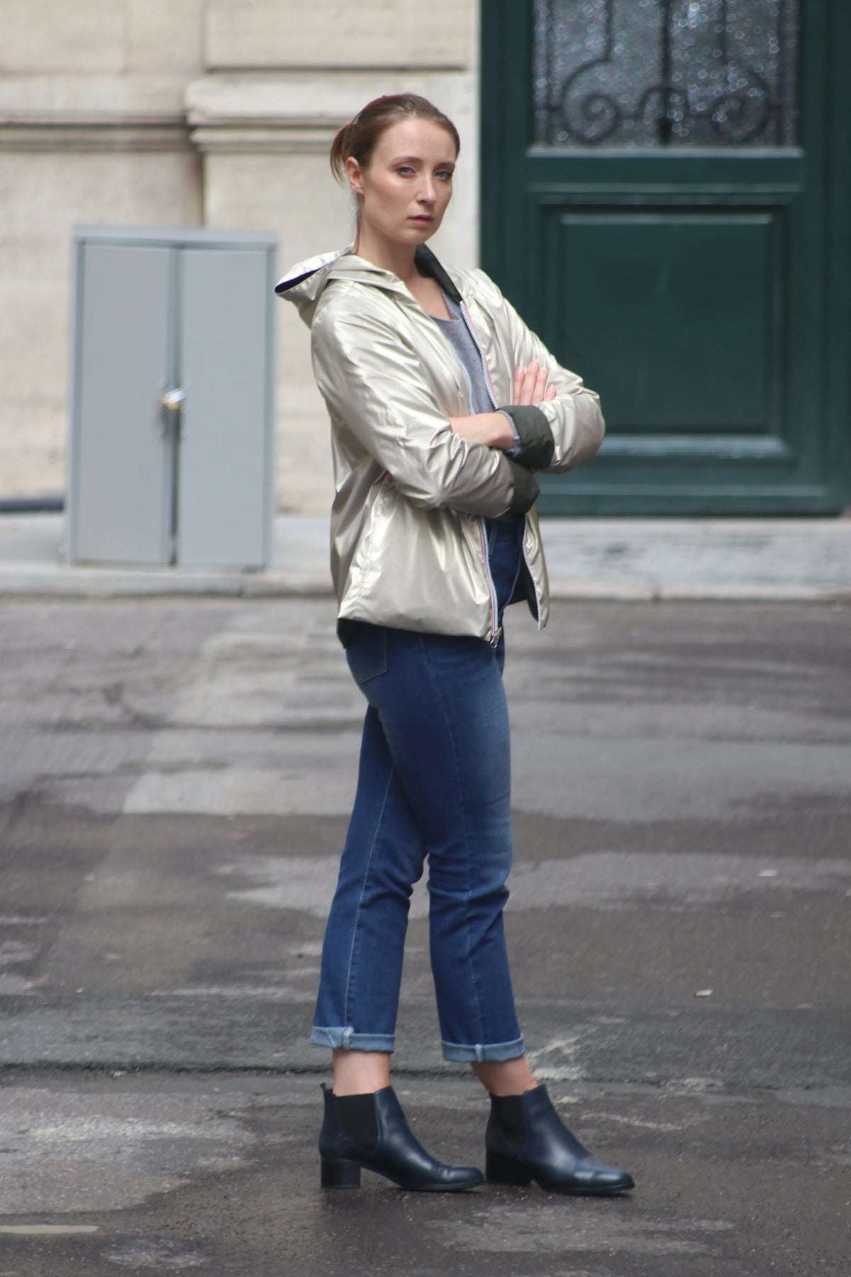 Femme portant une veste métallisée dorée, un jean bleu et des bottines noires en ville.