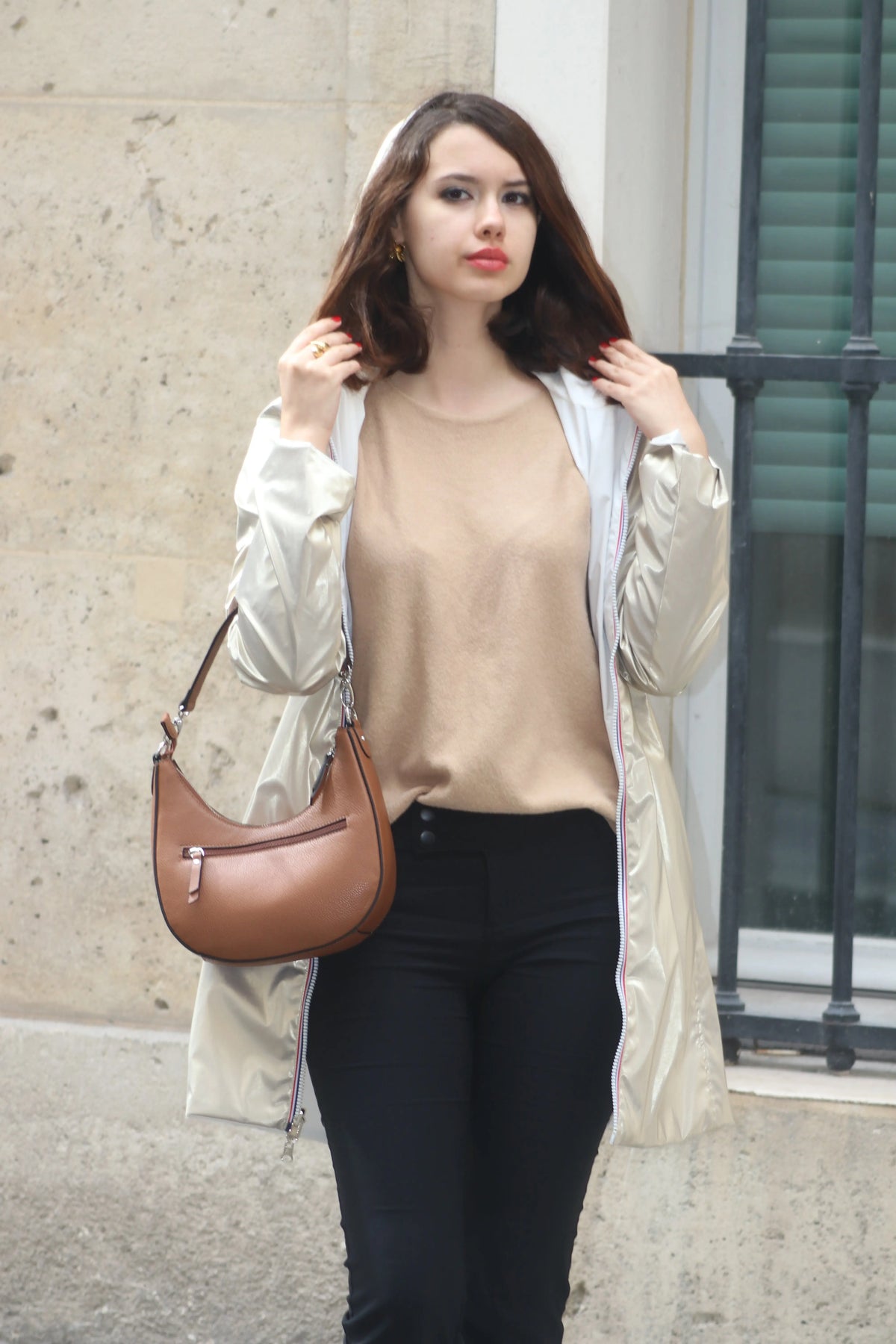 Femme portant un trench-coat beige clair, un pull nude et un sac à main marron.