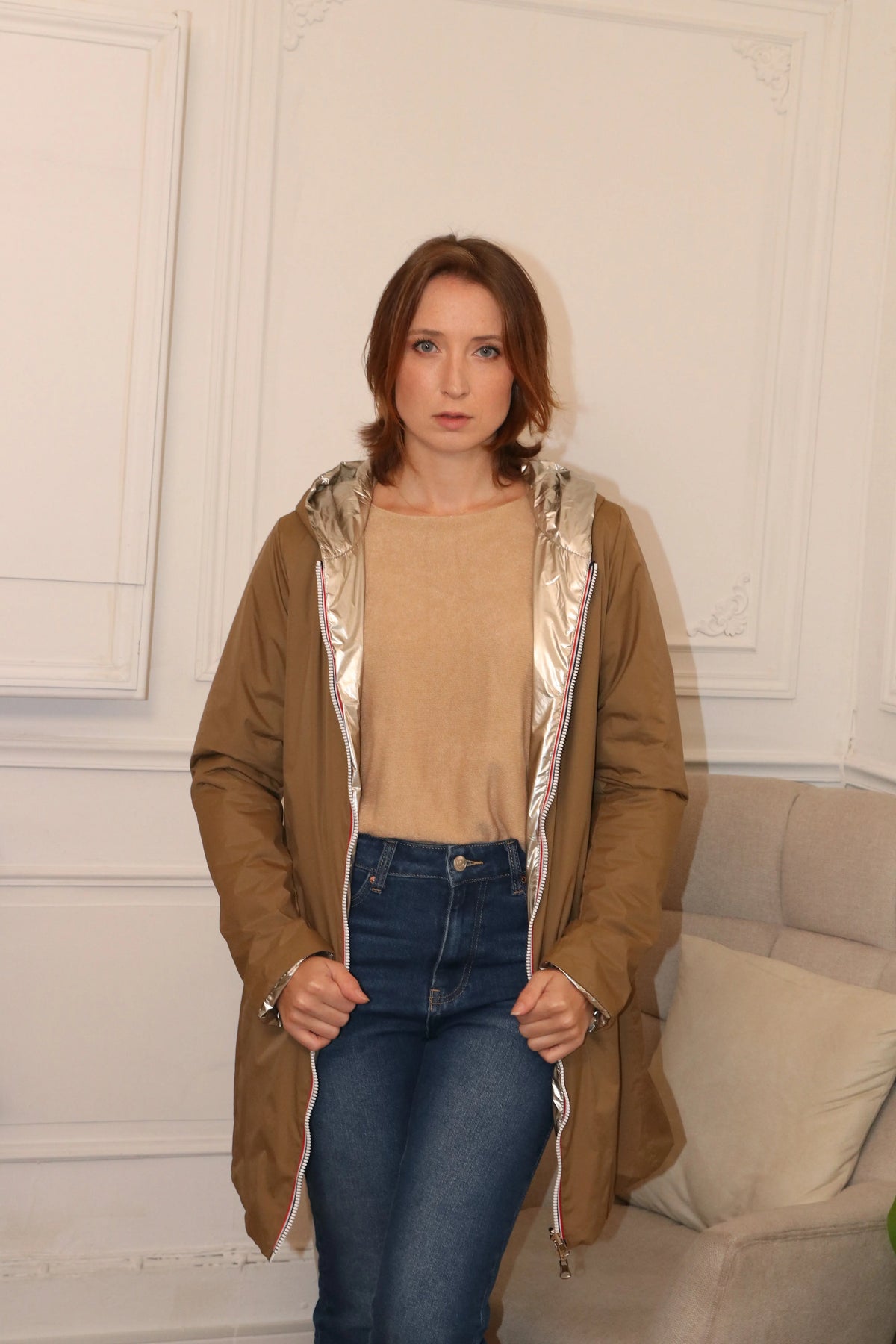 Femme portant un manteau beige léger sur un haut crème et un jean bleu