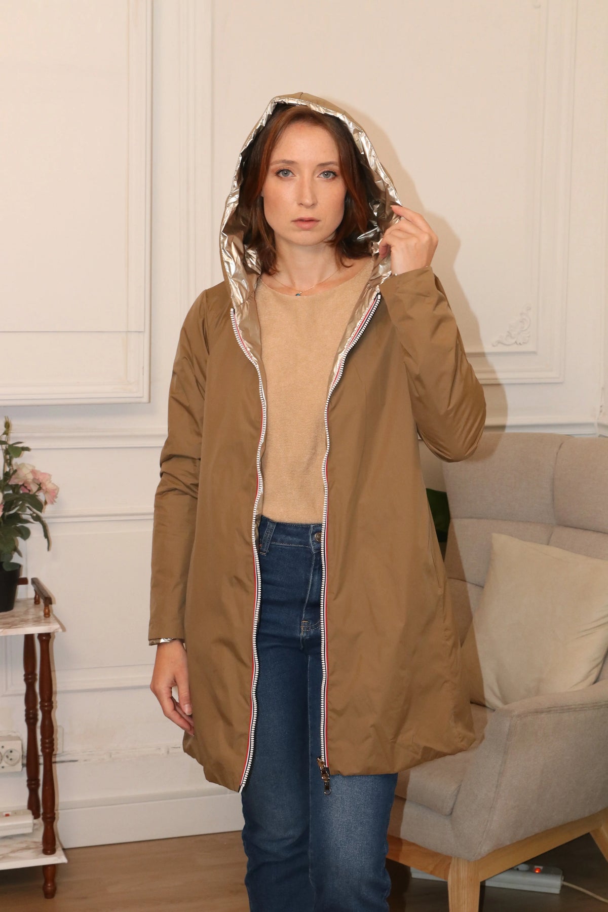 Femme portant un manteau beige à capuche doublée argentée et jean bleu