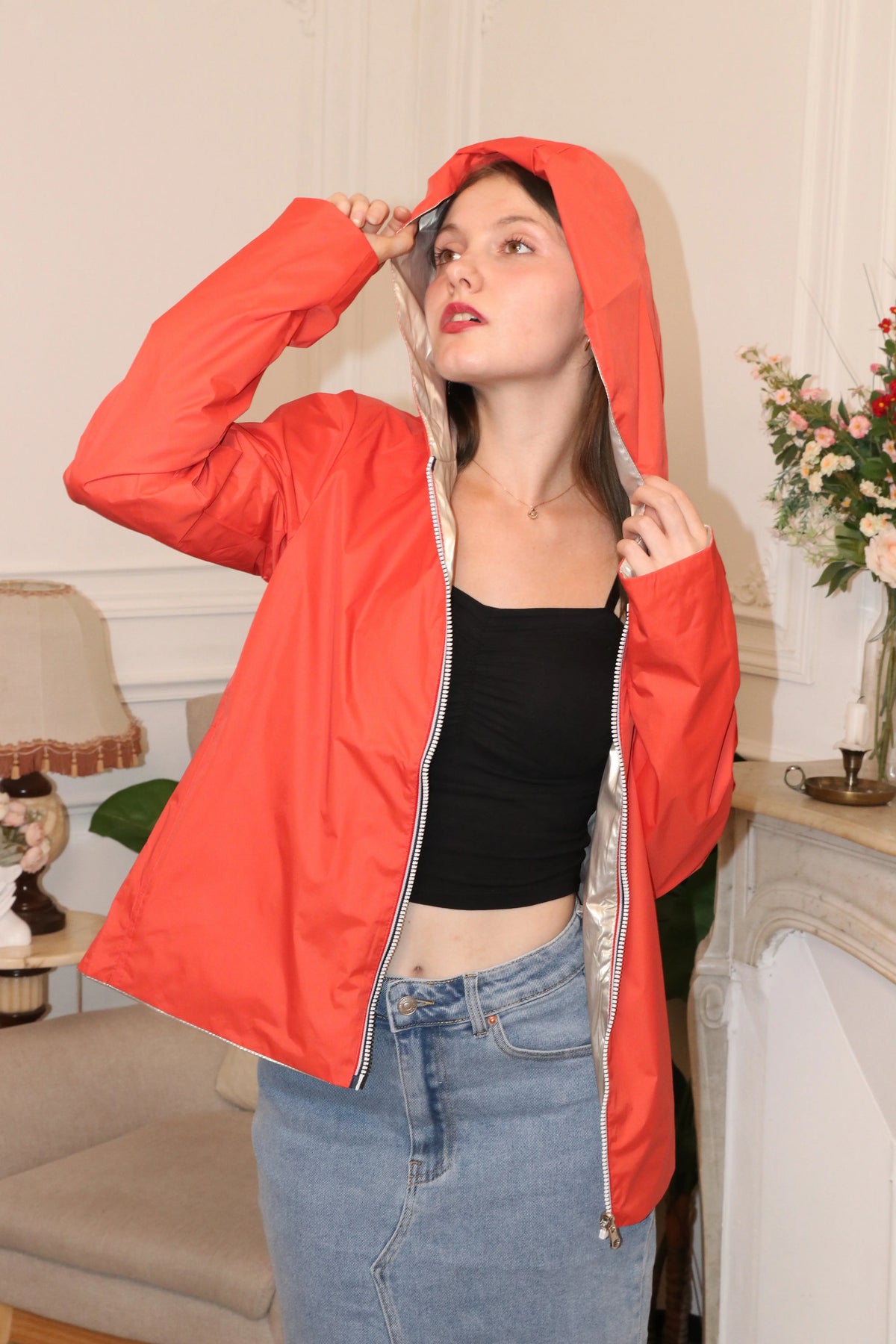 Femme portant une veste à capuche rouge et un débardeur noir avec une jupe en jean